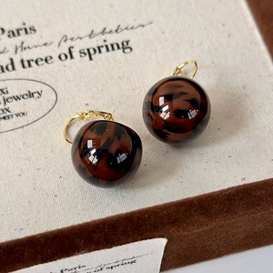 Macro view of leopard print sphere earrings with elegant gold metal hooks in detail