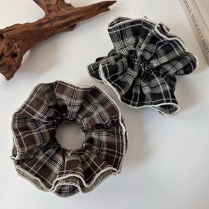 Detailed view of brown and black plaid scrunchies with elegant white lace trim accents