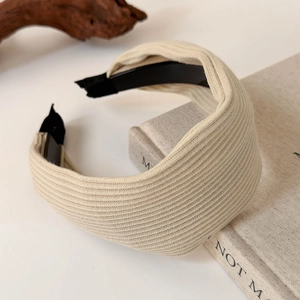 Close-up of beige knitted headband texture with ribbed pattern on minimalist surface
