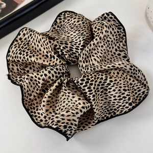 Close-up of leopard print scrunchie with delicate black piping and silk texture
