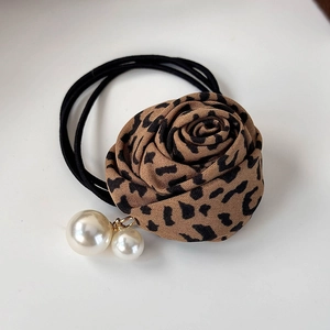Détail d'un chouchou rose en tissu imprimé léopard avec perles blanches nacrées