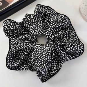 Detail of silk-like black and white dotted scrunchie with fine stitched edges and soft pleats