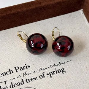 Detailed macro view of leopard print resin ball earrings with elegant gold leverback hooks