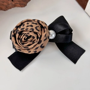 Détail de la pince à cheveux avec rose en tissu léopard, ruban noir et perle