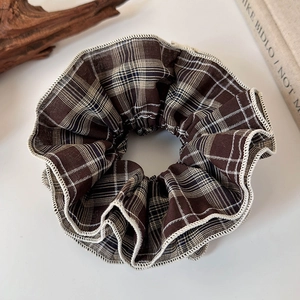 Macro shot of oversized vintage plaid hair scrunchie with layered fabric texture