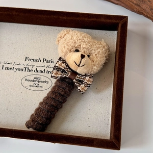 Détail de l'accessoire à cheveux ours en peluche avec nœud à carreaux et maille douce