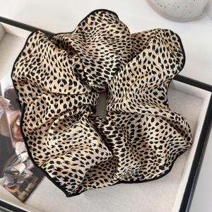 Detailed close-up of large leopard print scrunchie with elegant black stitched edges