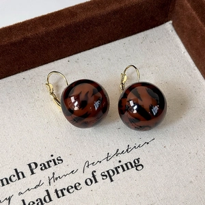 Detailed view of leopard print sphere earrings with elegant gold hook closure