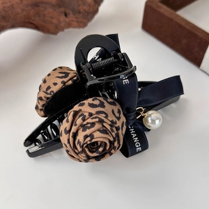 Détail de la pince à cheveux avec rose léopard, ruban noir et pendentif perle