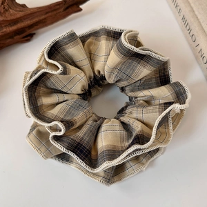 Close-up of vintage brown plaid scrunchie with white ruffled edges and fabric texture