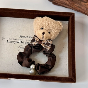 Vue détaillée d'un chouchou ours en peluche en satin marron et perles blanches