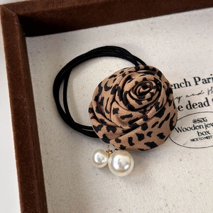 Gros plan sur l'élastique rose à motif léopard avec pendentifs en perles blanches