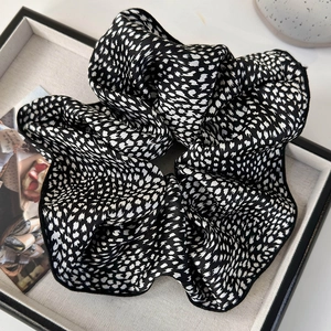 Detailed close-up of large black and white floral scrunchie on a jewelry tray