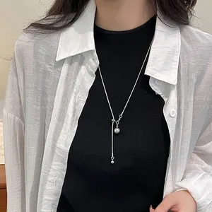 Détail d'un long collier en Y réglable argenté avec des pendentifs boules en métal