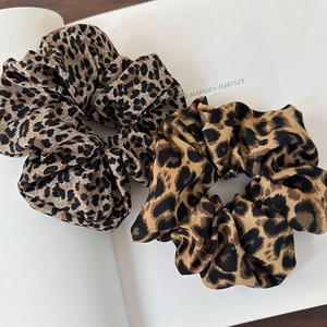Close-up of two leopard print satin scrunchies placed on an open fashion magazine