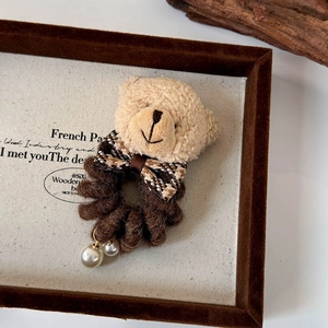 Détail de l'élastique ours en peluche avec nœud à carreaux marron et perles sur fond rétro