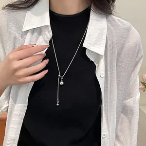 Collier en Y argenté ajustable avec boules métalliques porté par un mannequin chic