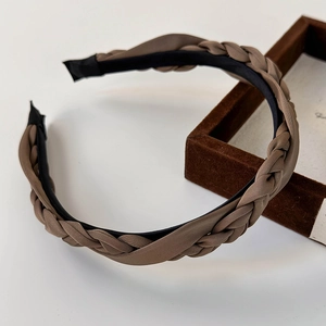Detail of a brown satin twisted headband with an elegant braided texture and black inner lining
