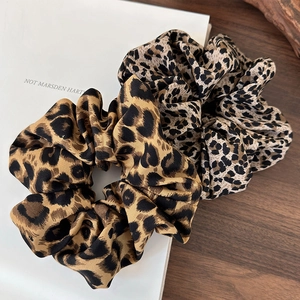 Macro shot of silk satin leopard print scrunchies with smooth texture and soft folds