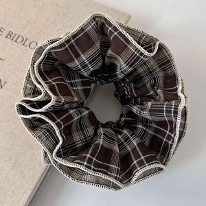 Detail of vintage brown plaid scrunchie with white stitching on aesthetic background