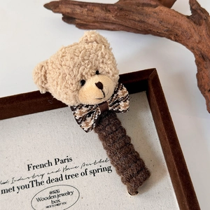 Détail de la pince à cheveux ours en peluche avec nœud pied-de-poule et manche tricoté