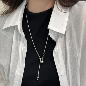 Détail d'un collier en Y réglable argenté avec boule métallique polie sur un mannequin