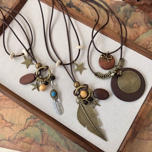 Ethnic vintage bronze necklace set with feather pendants and wooden beads on linen