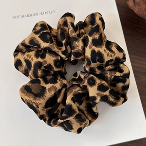 Detailed view of oversized leopard print scrunchie with pleated fabric texture on a book