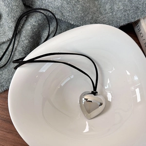 Détail du pendentif cœur argenté avec finition miroir dans un bol en céramique blanche