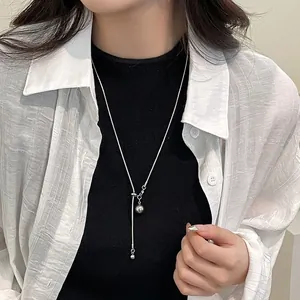 Détail d'un long collier en Y argenté avec pendentif boule en métal ajustable sur mannequin