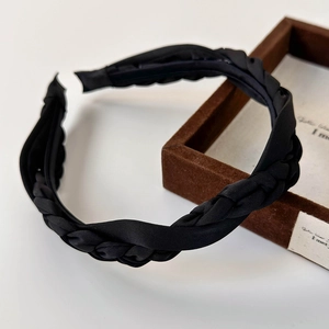 Detail showing high-shine black satin braided headband with intricate twisted texture