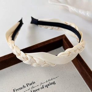 Close-up of cream satin braided headband with French vintage twist design on velvet tray