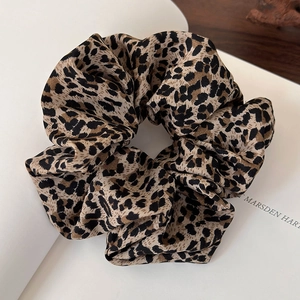 Close-up detail of leopard print hair scrunchie with soft silk texture and pleated design