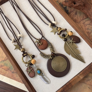 Close-up of Bohemian layered necklaces with wood pendants and feathers in a wooden tray