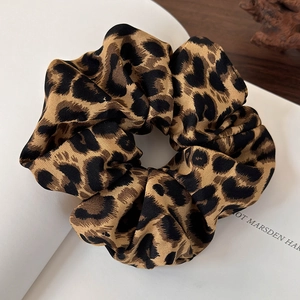 Close-up of leopard print satin scrunchie with glossy texture on open book