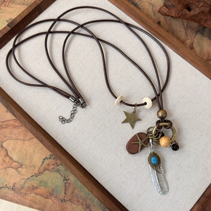 Detailed close-up of a vintage ethnic necklace featuring metallic feather and wooden charms