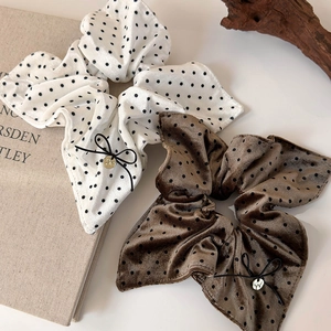 Macro detail of velvet polka dot scrunchies with black bows and golden pendants