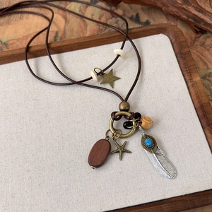 Detail of ethnic beaded necklace featuring wooden beads and feather pendant on canvas