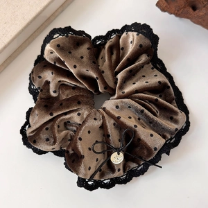 Close-up of brown velvet polka dot hair scrunchie with black lace and golden pendant