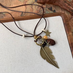 Close-up of ethnic beaded necklace featuring bronze feathers and wooden charms