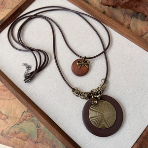 Detail view of ethnic wooden pendant necklace with bronze metal and feather motifs
