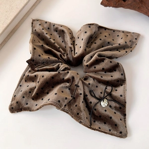 Detail of coffee velvet scrunchie with black polka dots, bow, and gold pendant charm