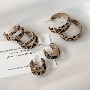 Macro shot of three leopard print C-shape hoop earrings with matte finish on white prop card
