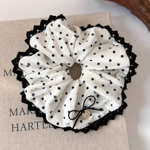 Detail of velvet polka dot scrunchie with lace edges, ribbon bow and gold pendant charm