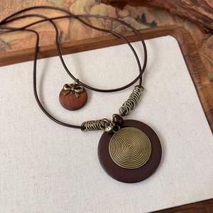 Macro shot of ethnic style wooden pendant with bronze spiral metal and layered wax cords
