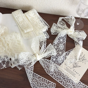 Close-up of vintage cream lace ribbon with intricate floral embroidery on wooden table