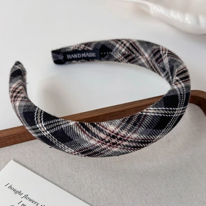 Detail of a plaid wide headband showing the handmade label and classic woven texture