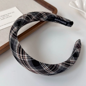 Macro shot of plaid padded headband with handmade label on a clean white surface
