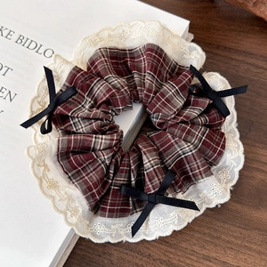Detailed close-up of retro plaid hair scrunchie with lace trim and black ribbon bows