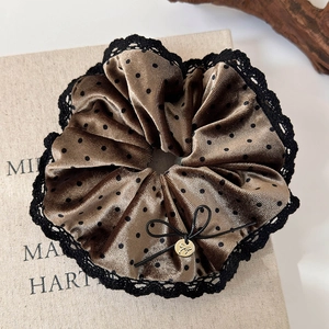 Detail of coffee velvet scrunchie with polka dots, lace edges and a golden charm